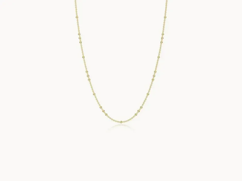 A delicate gold chain necklace with small beads evenly spaced along its length.