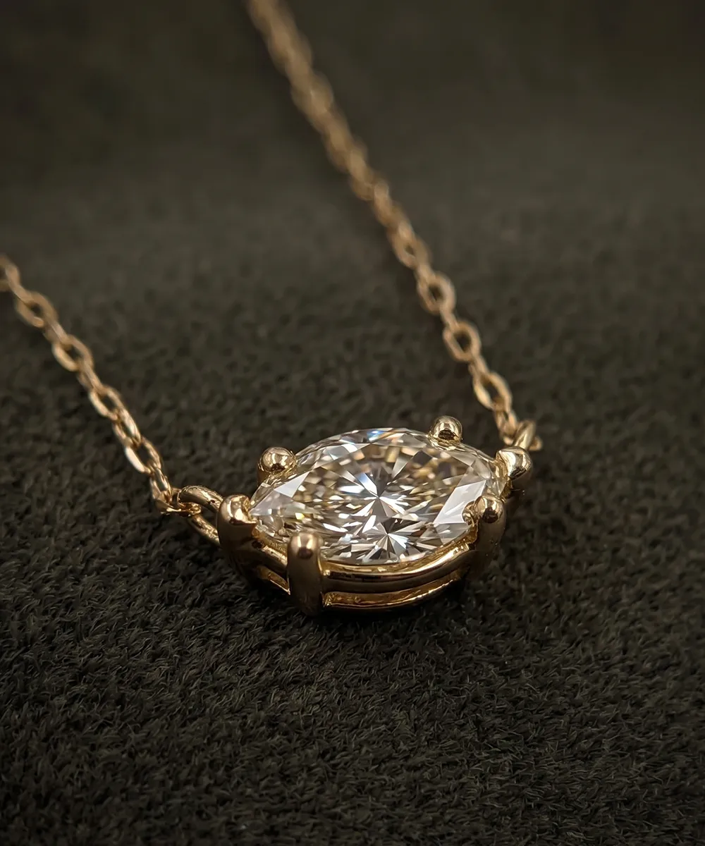 A gold necklace with a large, sparkling diamond pendant on a dark textured background.