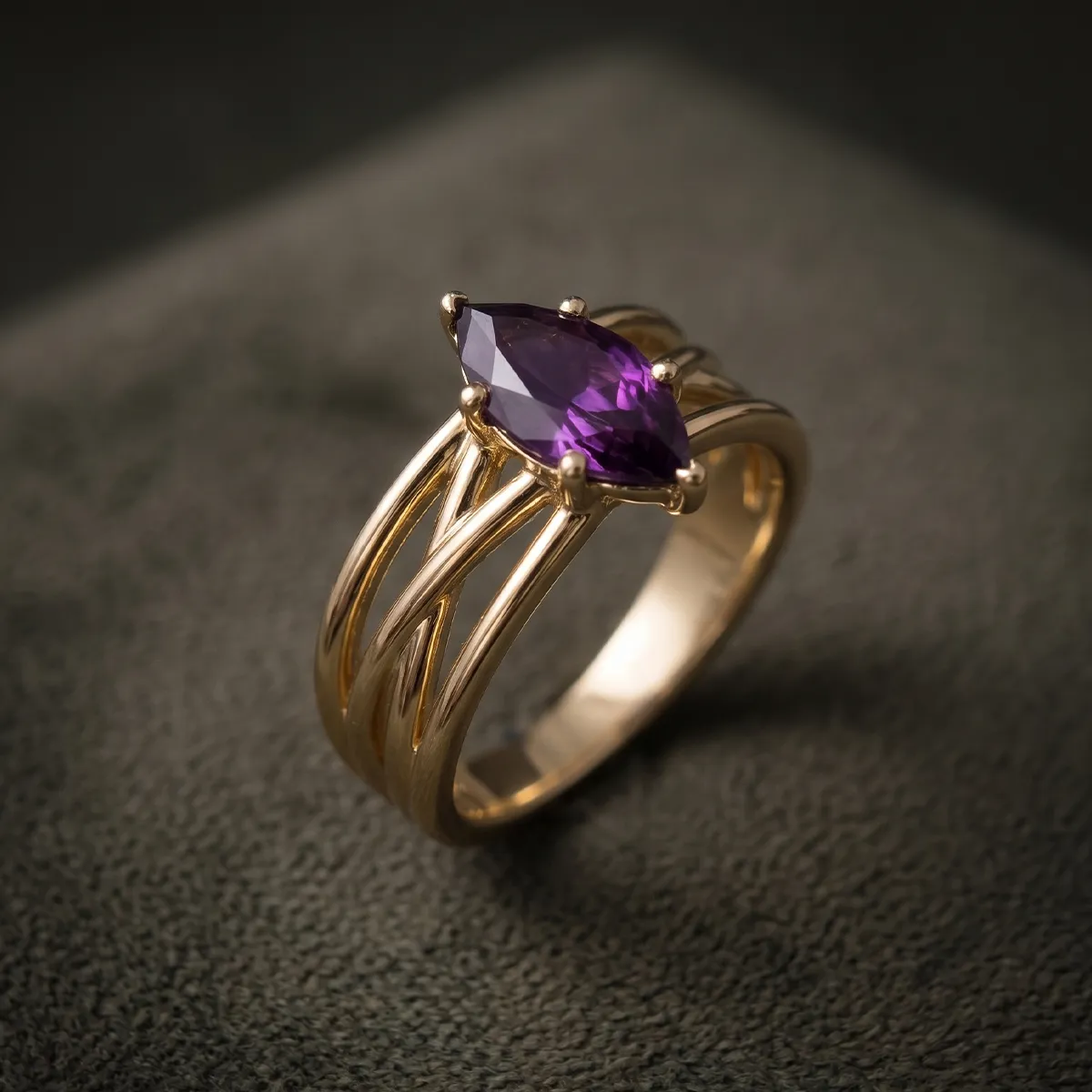 A gold ring with a marquise-cut purple gemstone on a textured surface.