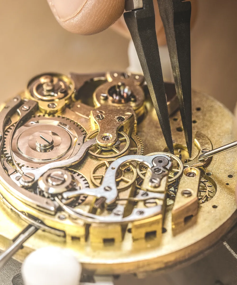 Close-up of a watch mechanism being repaired with tweezers.