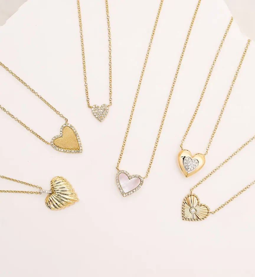 Heart-shaped blue gemstone pendant necklace with diamonds, worn on a black sweater.