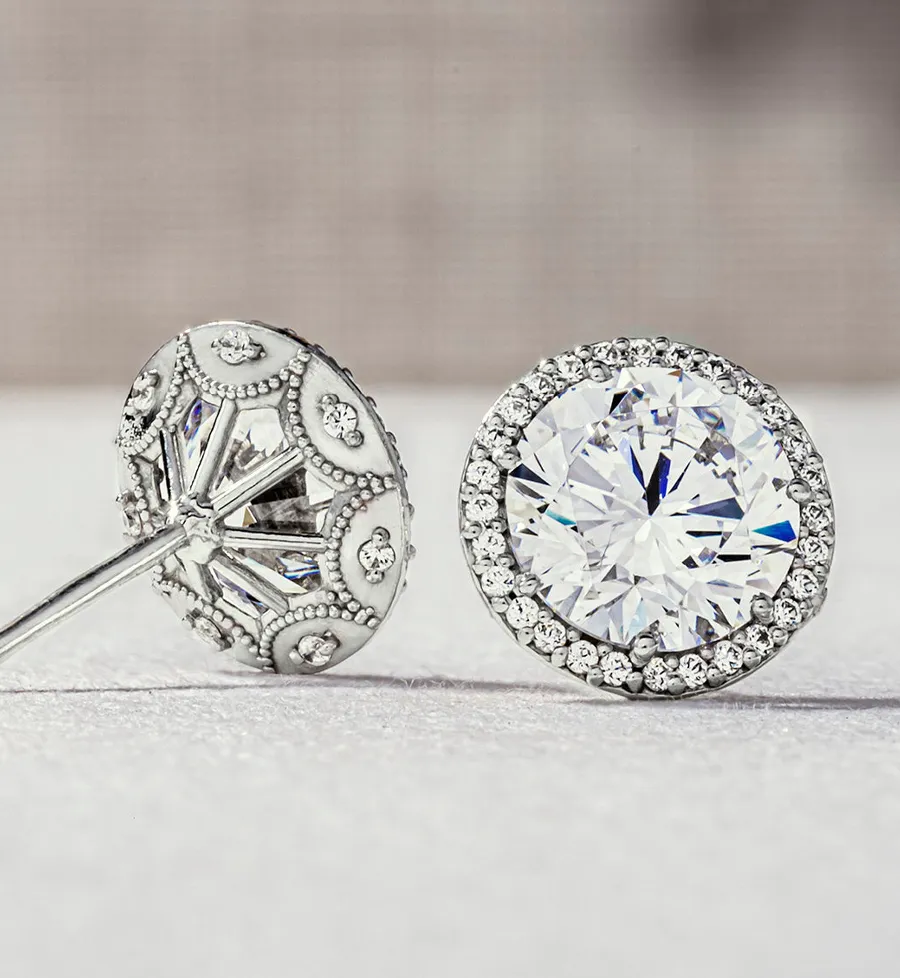 Diamond stud earrings with intricate silver detailing, showcasing a round brilliant cut diamond.