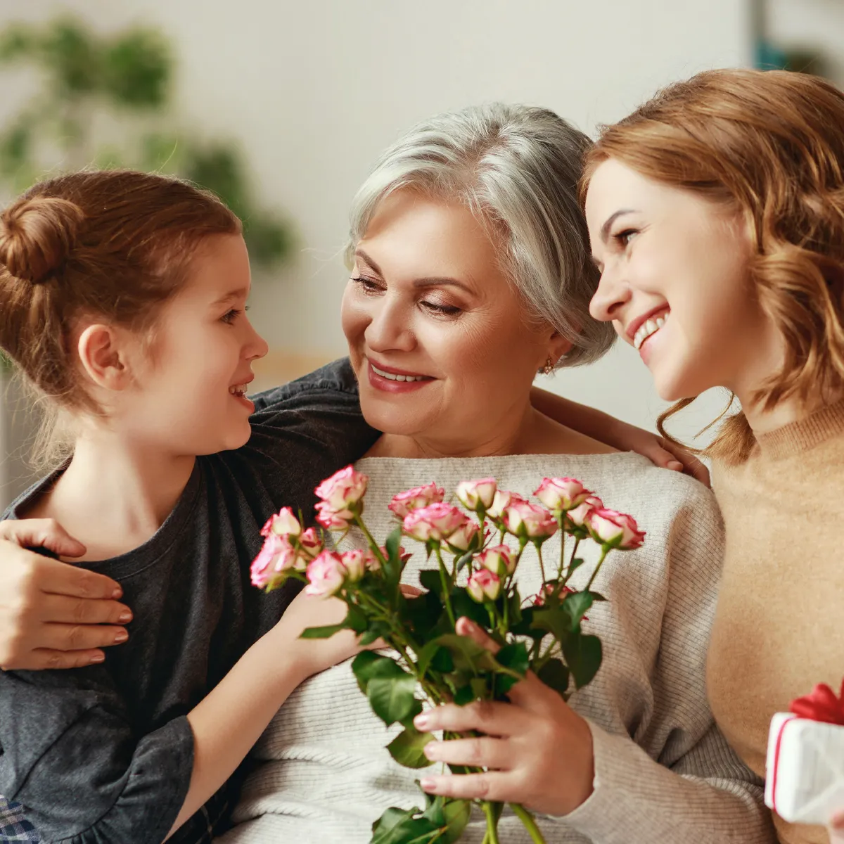 A grandmother, mother, and daughter share a joyful moment with flowers.