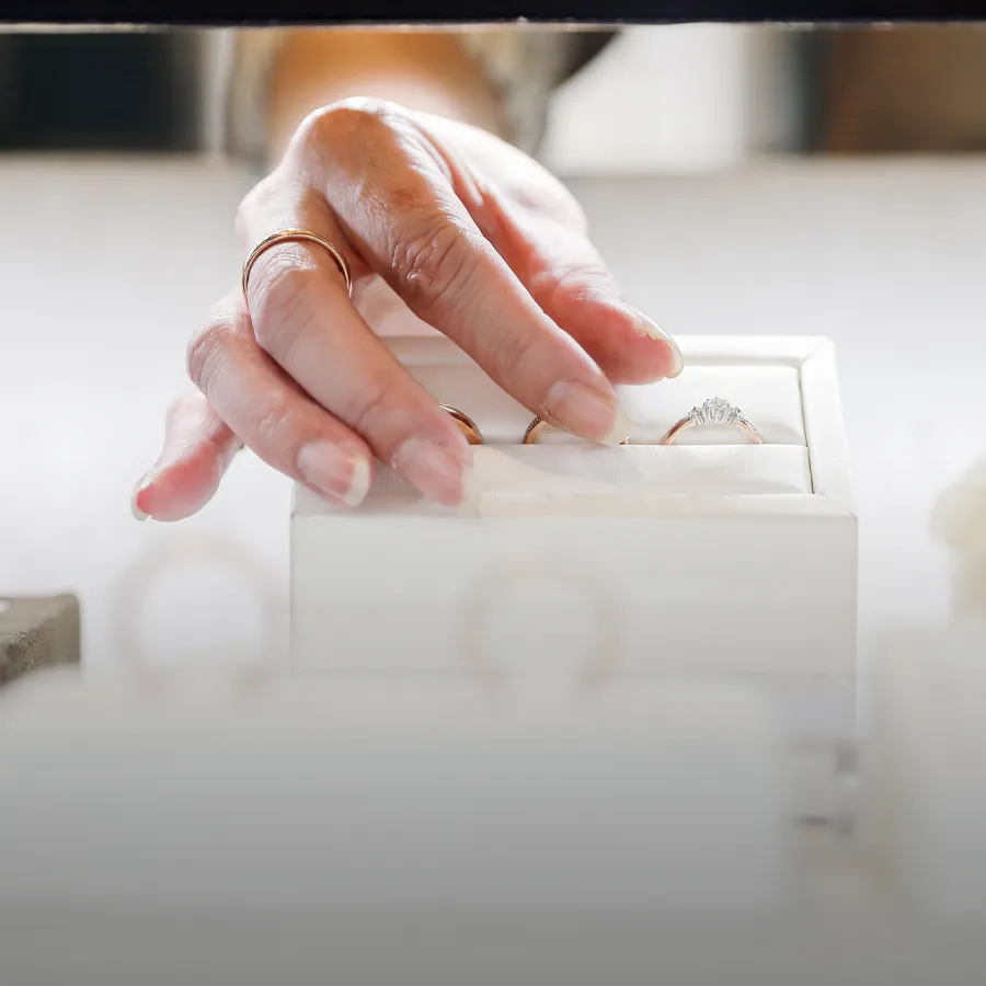 A hand reaching for engagement rings in a jewelry display case.