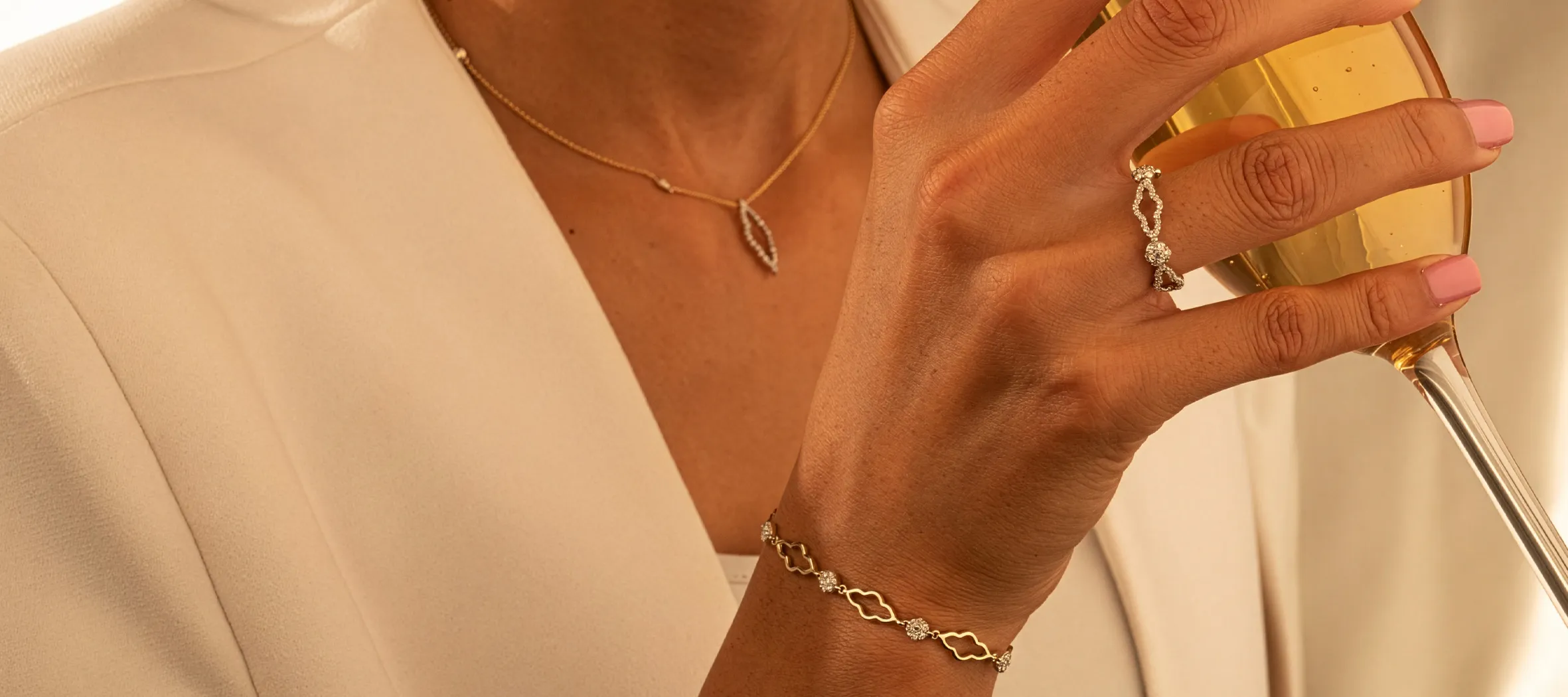 Elegant jewelry display featuring a necklace, ring, and bracelet, with a woman holding a glass of champagne.