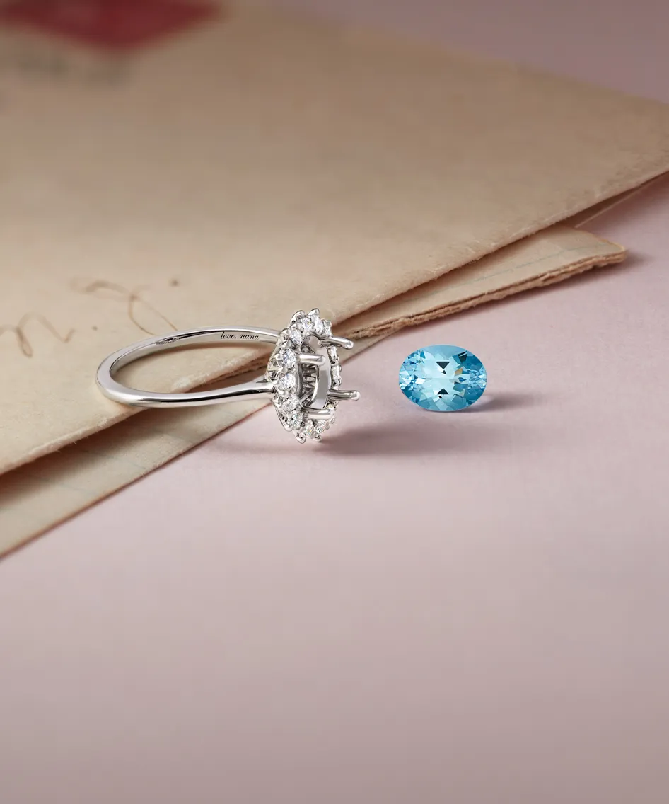 A silver engagement ring with a blue gemstone beside it, resting on vintage paper.