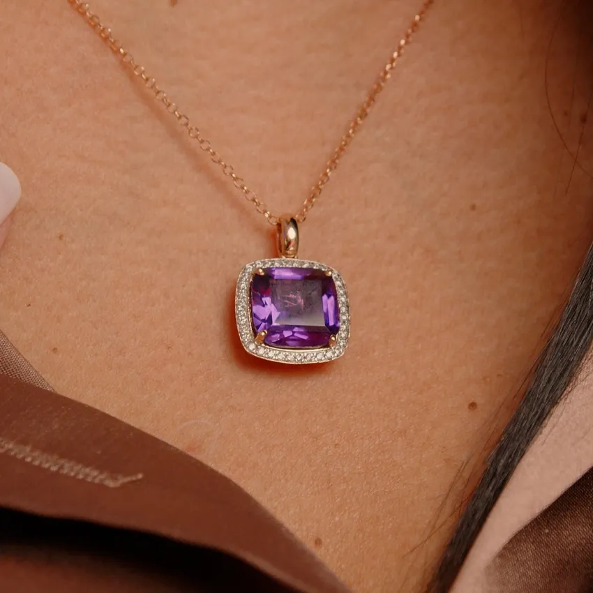 Amethyst pendant necklace with diamond accents, worn on a woman's neck.