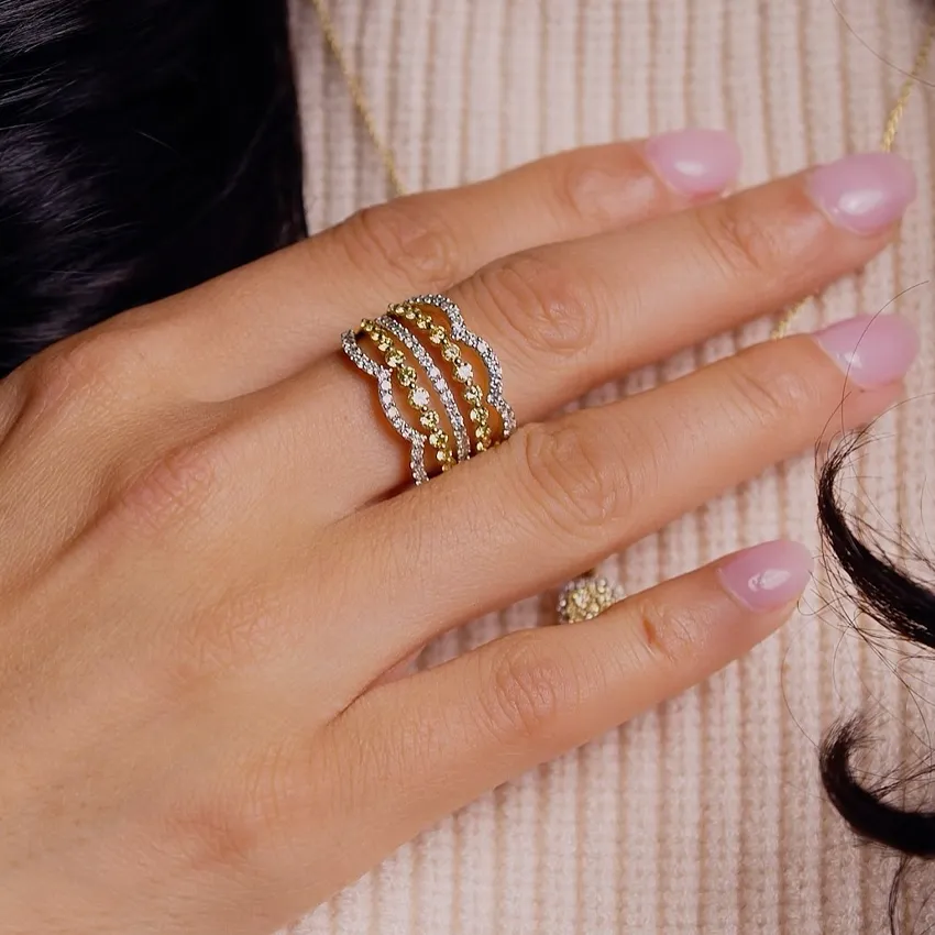 Gold and diamond wave ring worn on a hand, showcasing elegant jewelry.