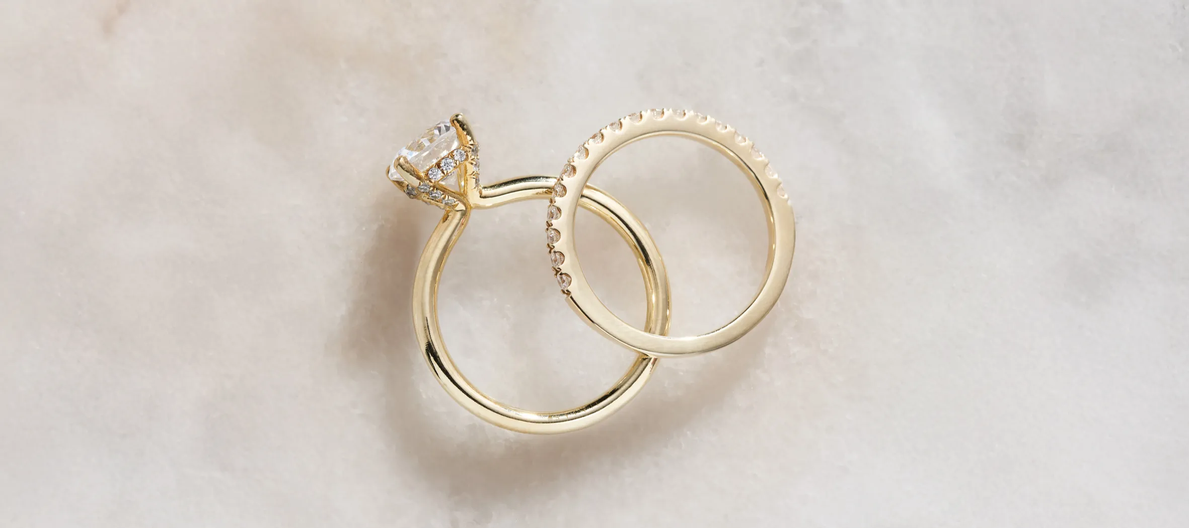 Two elegant gold rings, one with a diamond, displayed on a soft surface.