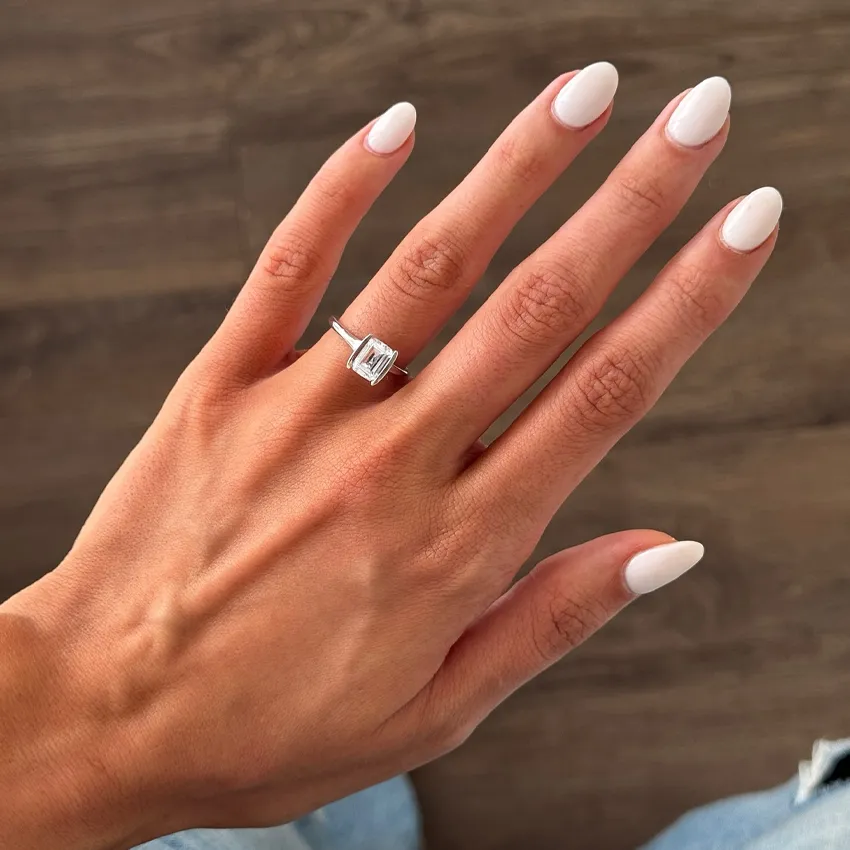 Elegant hand with a silver engagement ring and manicured nails.