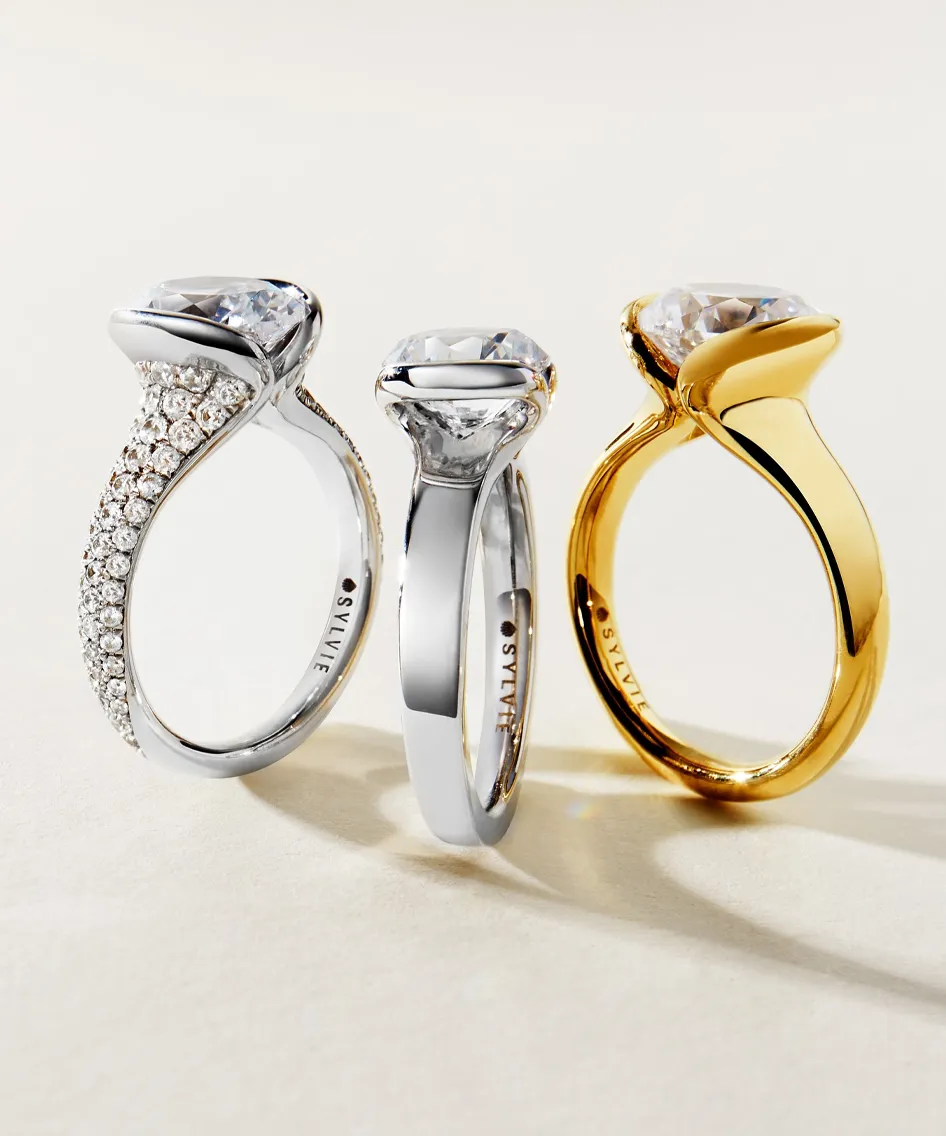 Three elegant engagement rings: one silver with diamonds, one simple silver, and one gold.