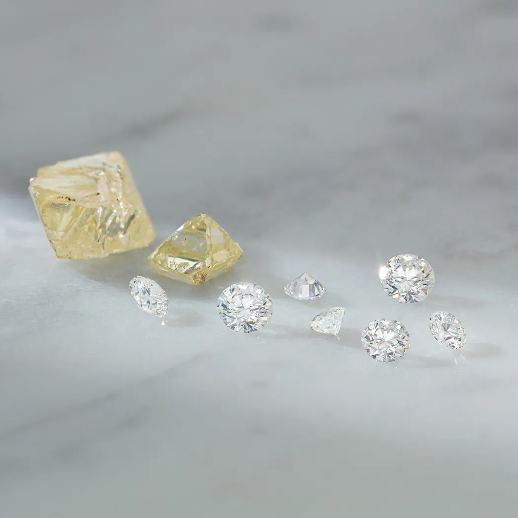 A collection of sparkling diamonds and yellow gemstones on a marble surface, showcasing fine jewelry options.