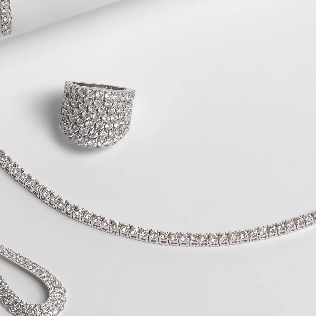 Elegant silver jewelry set featuring a ring, necklace, and earrings with sparkling stones.