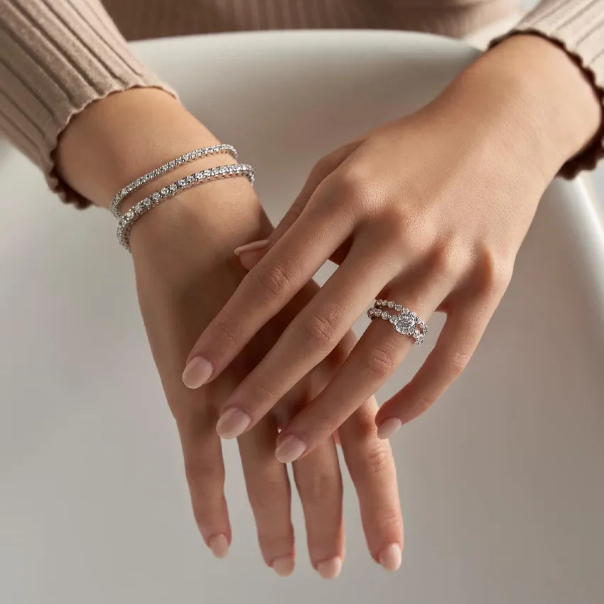 Elegant hands adorned with diamond bracelets and a ring.