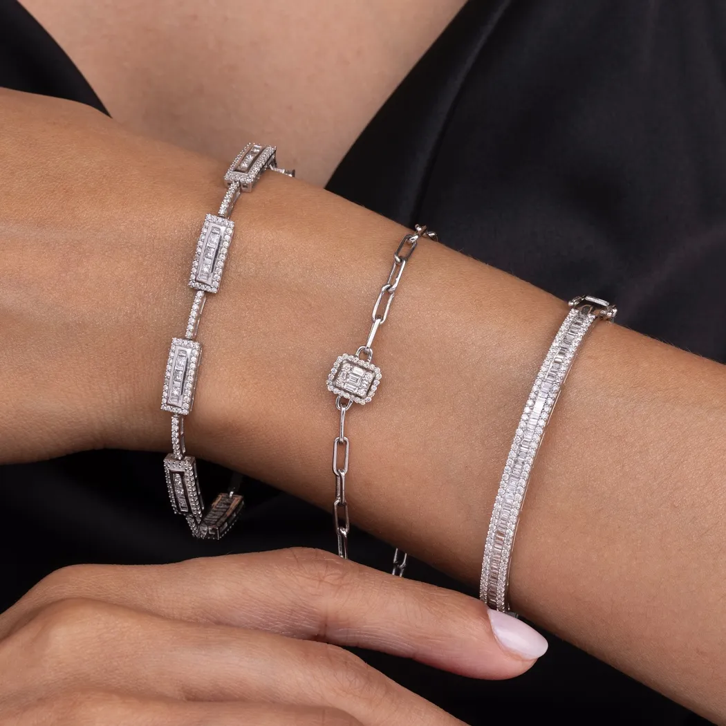 Three elegant silver bracelets with diamonds on a woman's wrist.