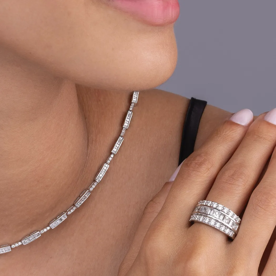 Close-up of a woman wearing a diamond necklace and stacked rings.