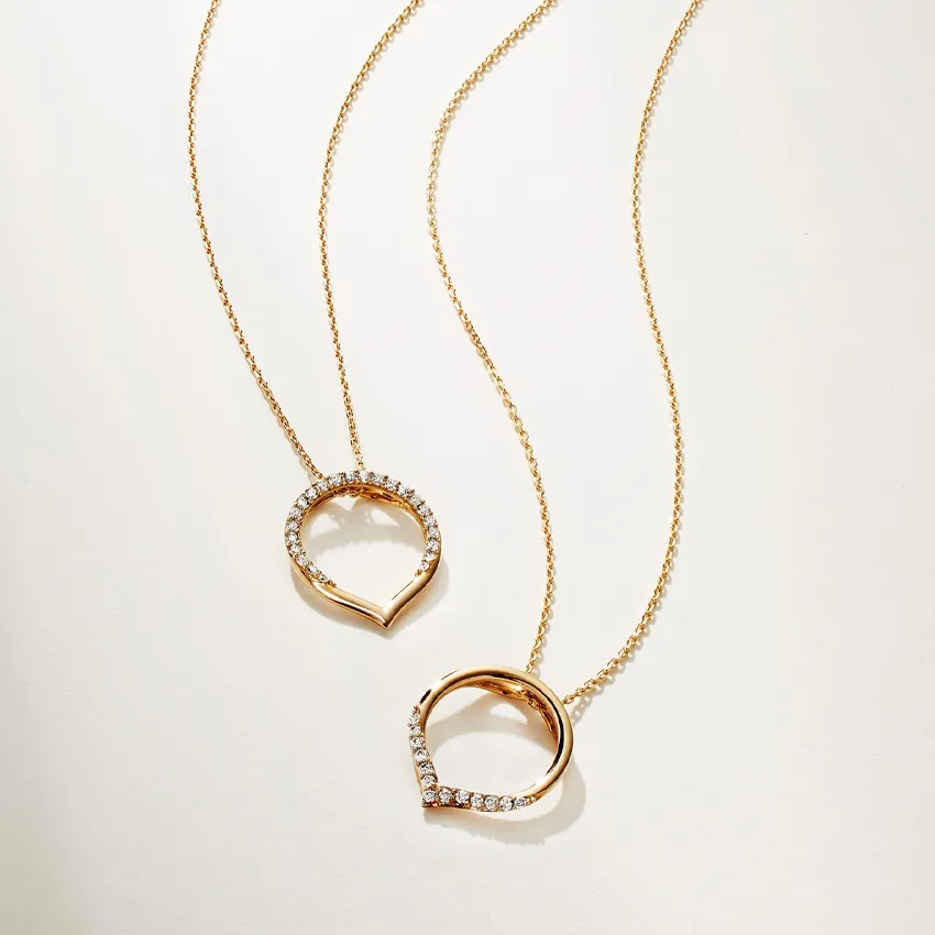 Two elegant gold necklaces with heart-shaped pendants adorned with sparkling diamonds.