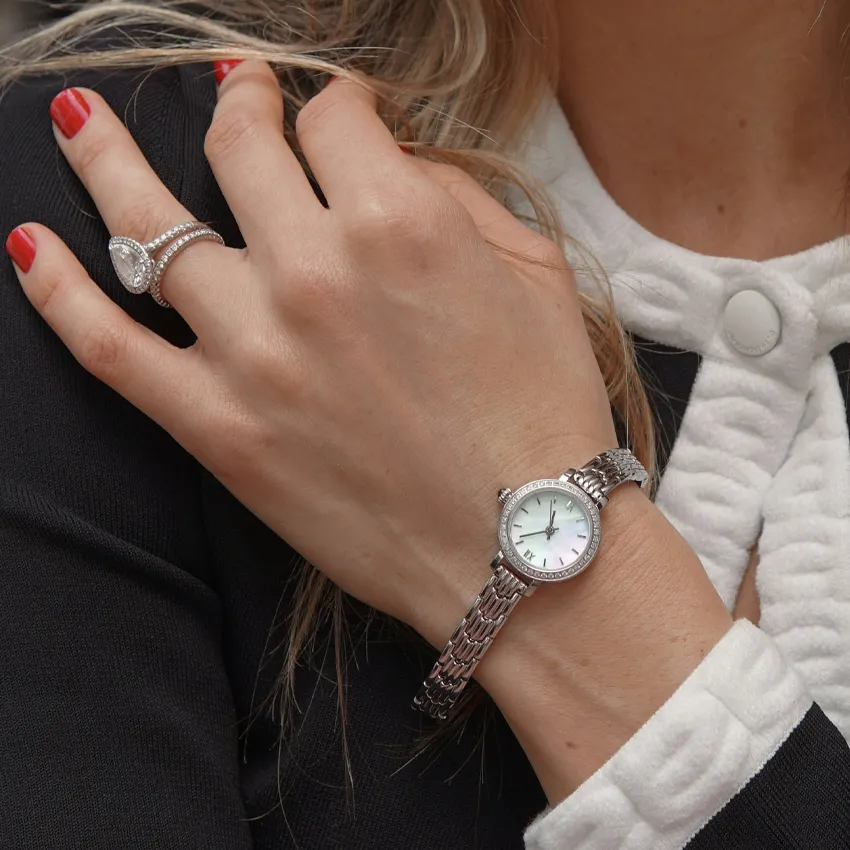 Close-up of a woman's hand wearing a silver watch and a diamond ring, showcasing elegant jewelry.