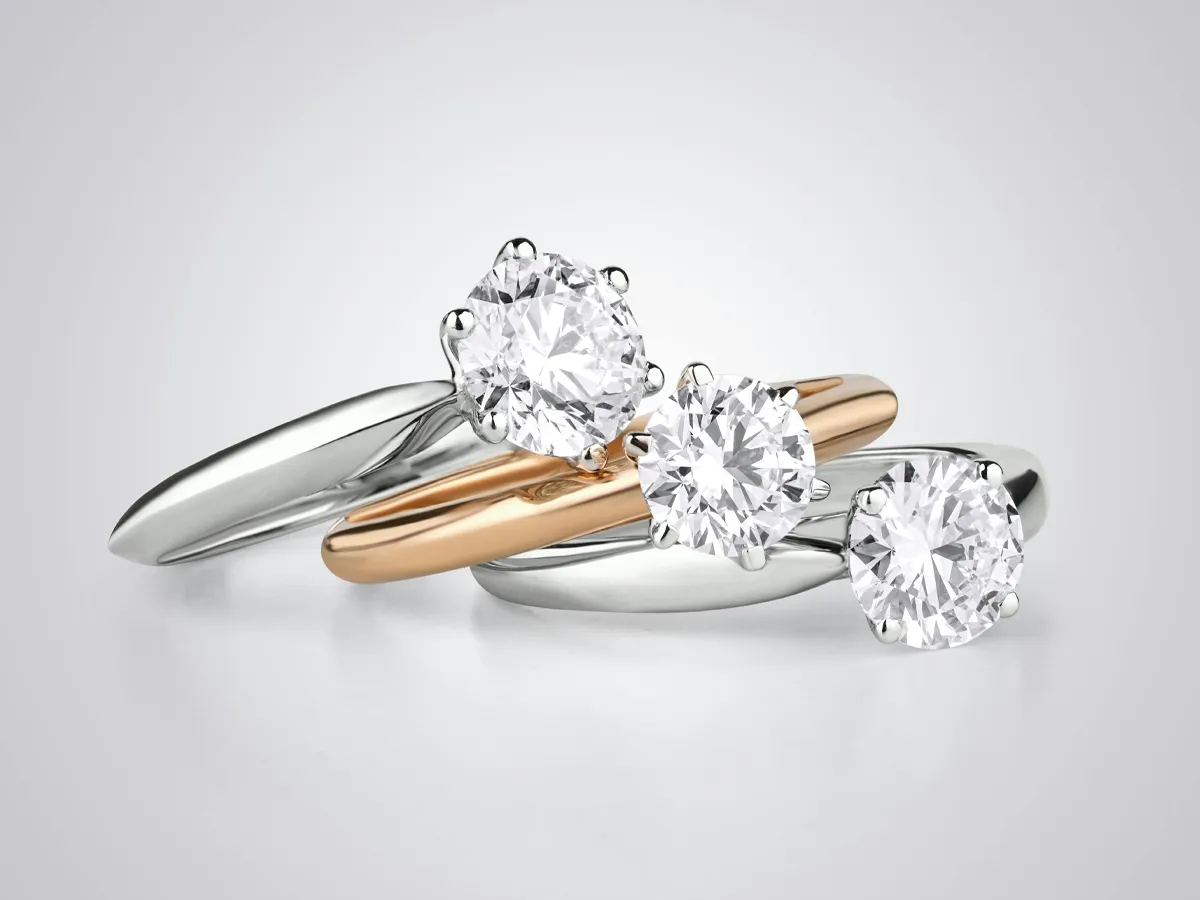 Three elegant engagement rings featuring round diamonds in white and rose gold settings.