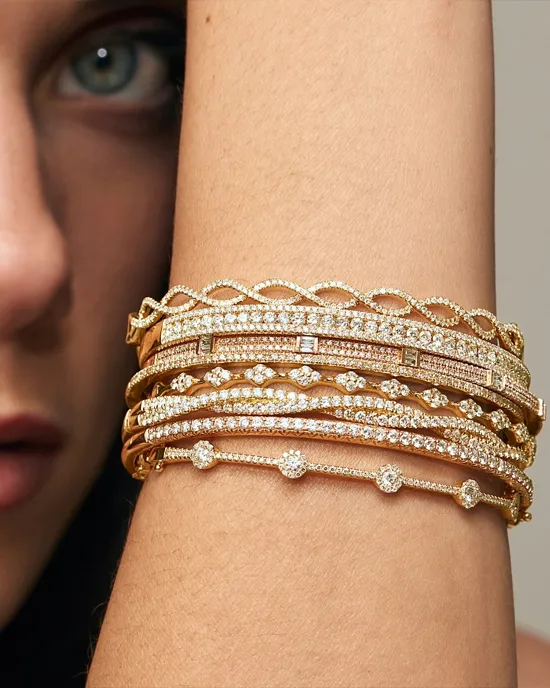 Close-up of a woman's arm adorned with multiple elegant gold and diamond bracelets.