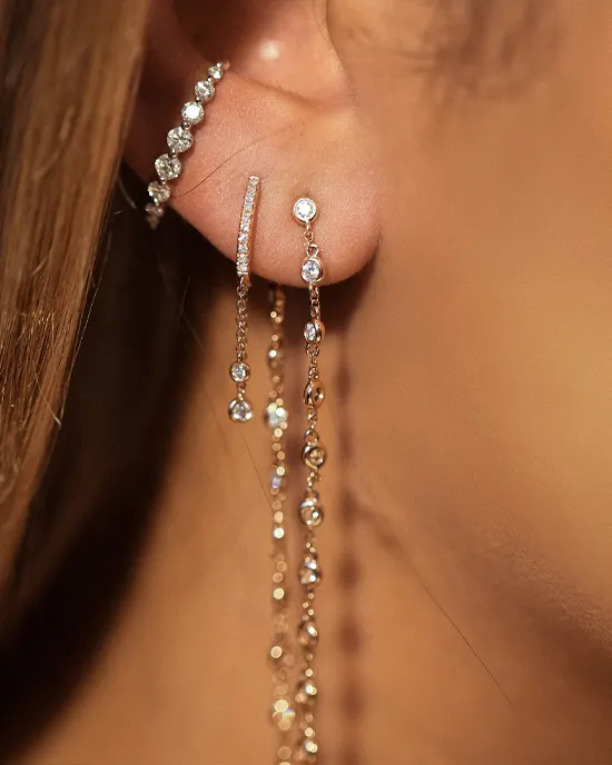 Close-up of elegant earrings featuring sparkling gems and chains, showcasing fine jewelry.