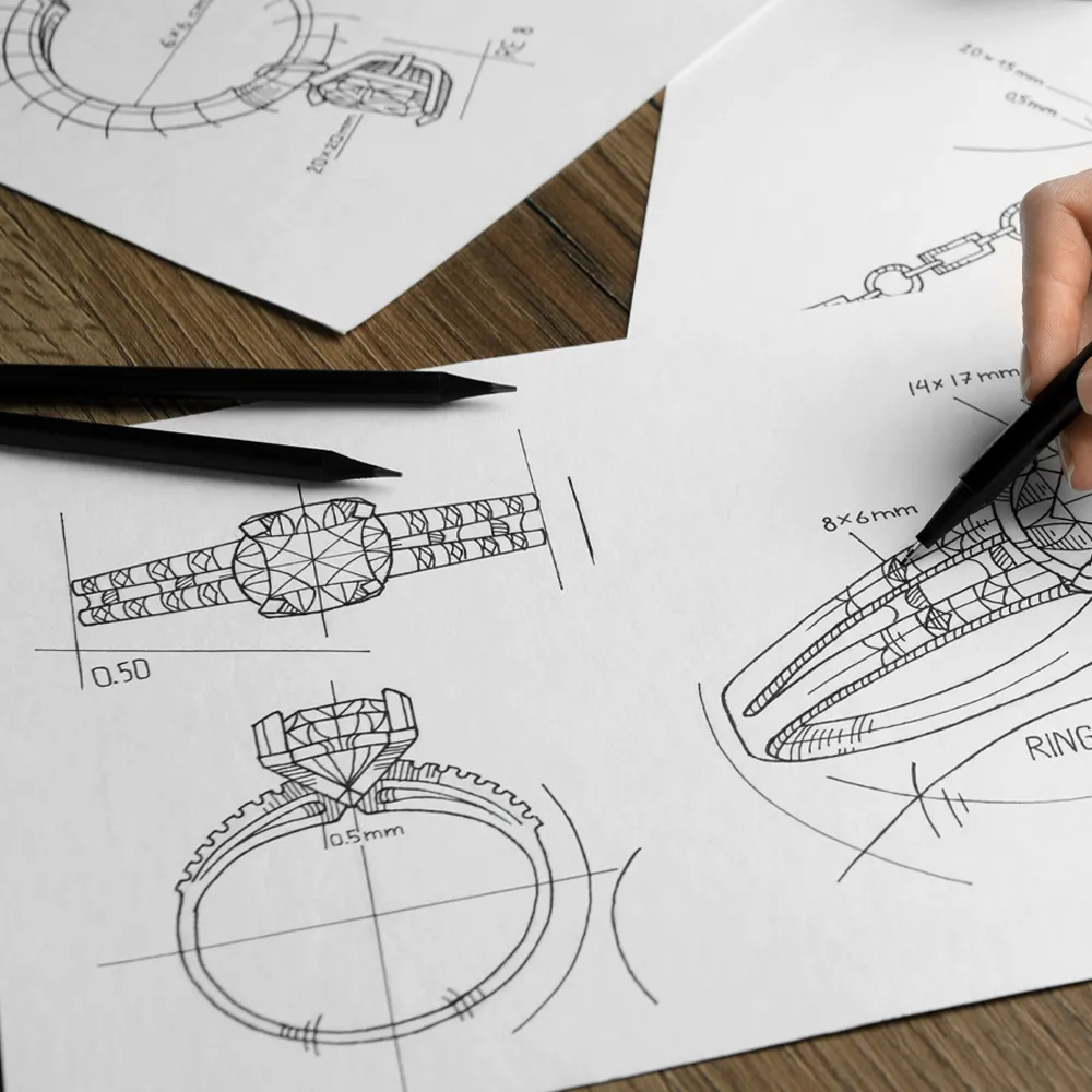 Sketches of jewelry designs with a hand holding a pencil, showcasing detailed ring illustrations. 
