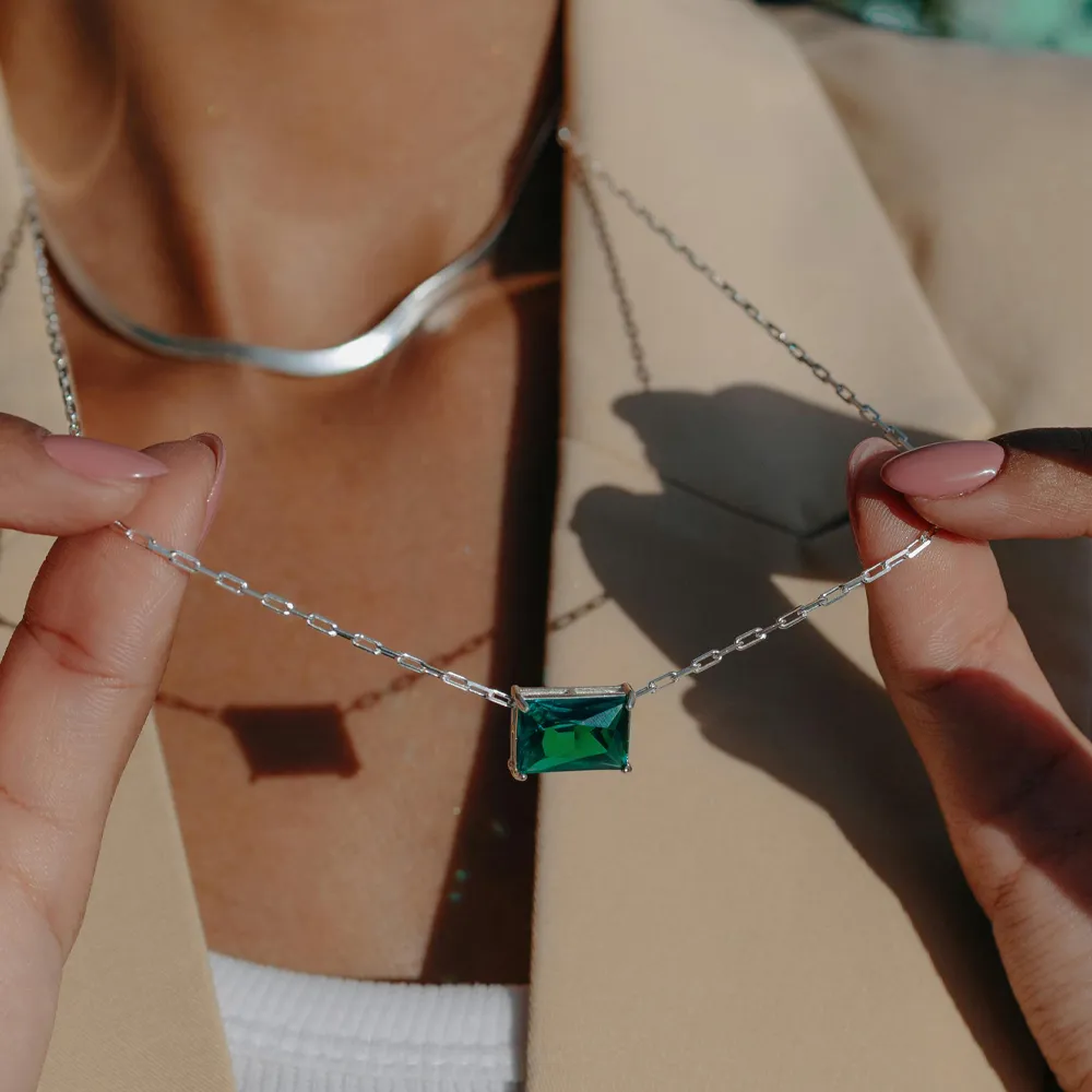Model showcasing a silver chain necklace with a green gemstone pendant. Shop at Diamelo, NYC for fine jewelry.