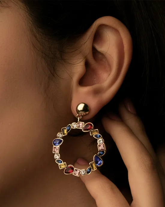 Colorful gemstone hoop earrings worn by a model, showcasing a mix of vibrant stones and gold accents.