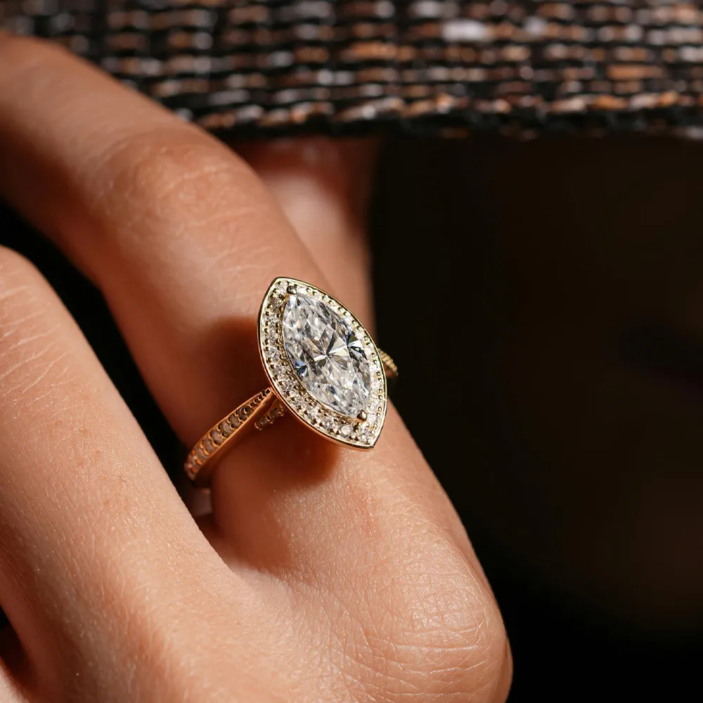Elegant marquise diamond ring with halo, set in gold, showcased on a hand. 