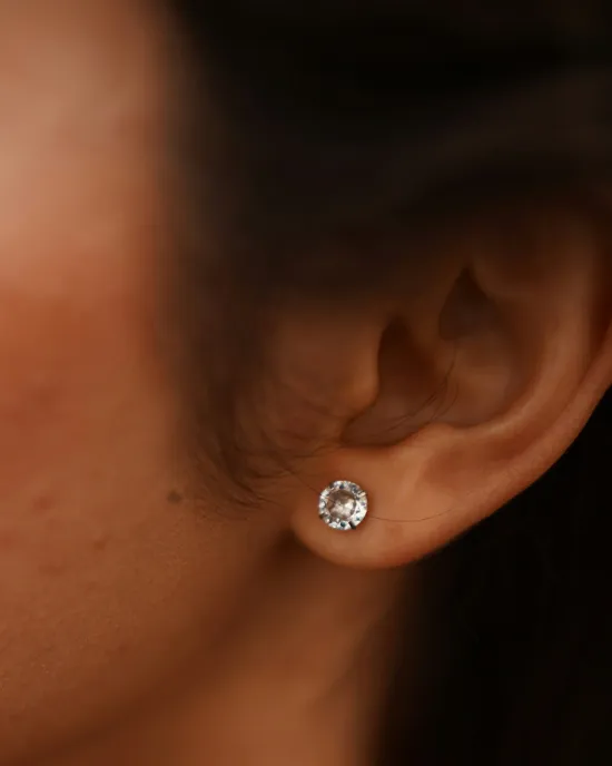 Close-up of a woman's ear with a sparkling diamond stud earring. 