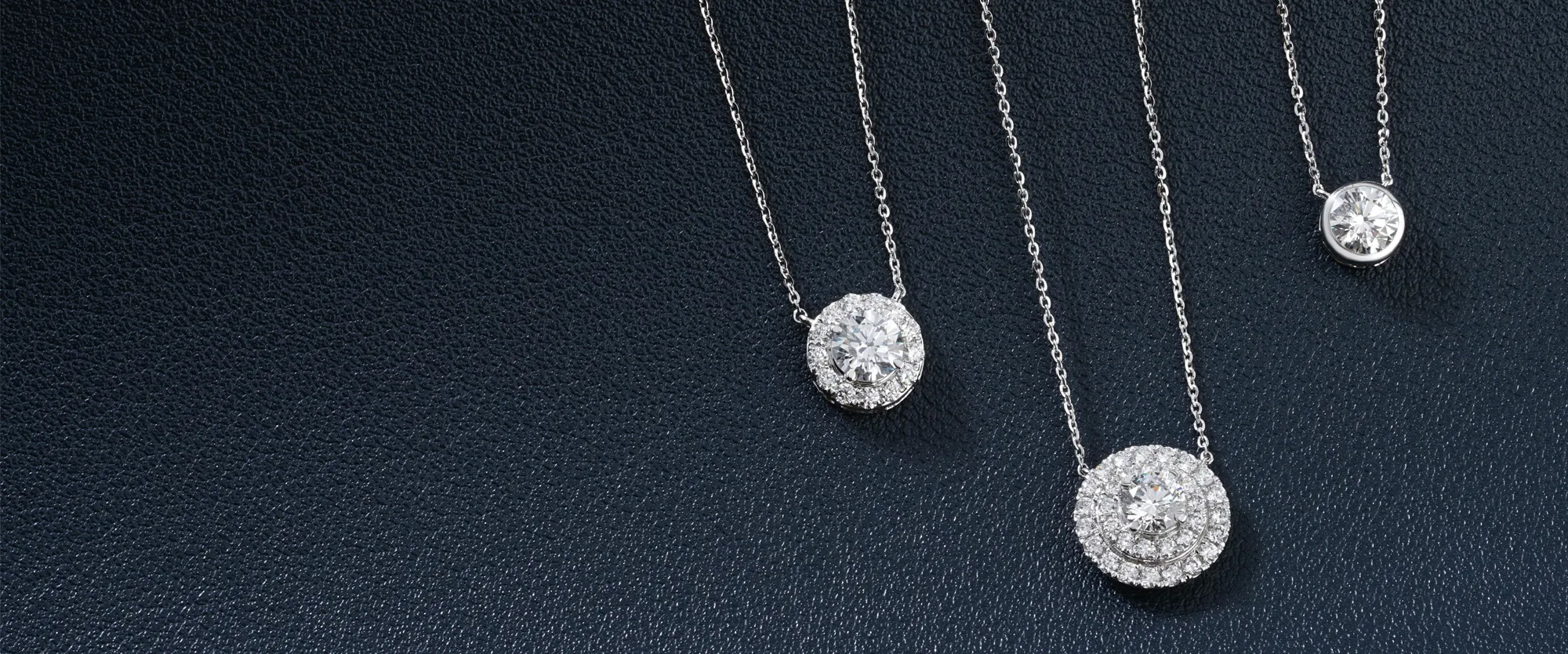 Three elegant diamond necklaces on a dark textured background. 