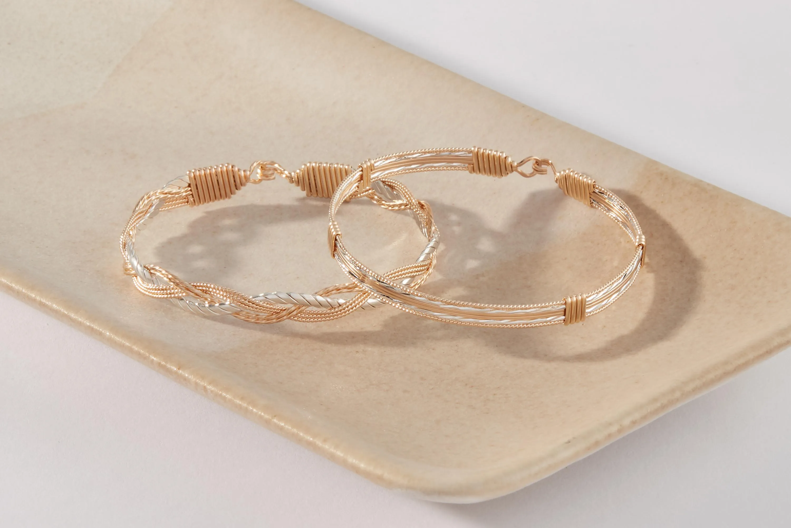 A collection of gold and pearl bangles with intricate designs on a light blue background.
