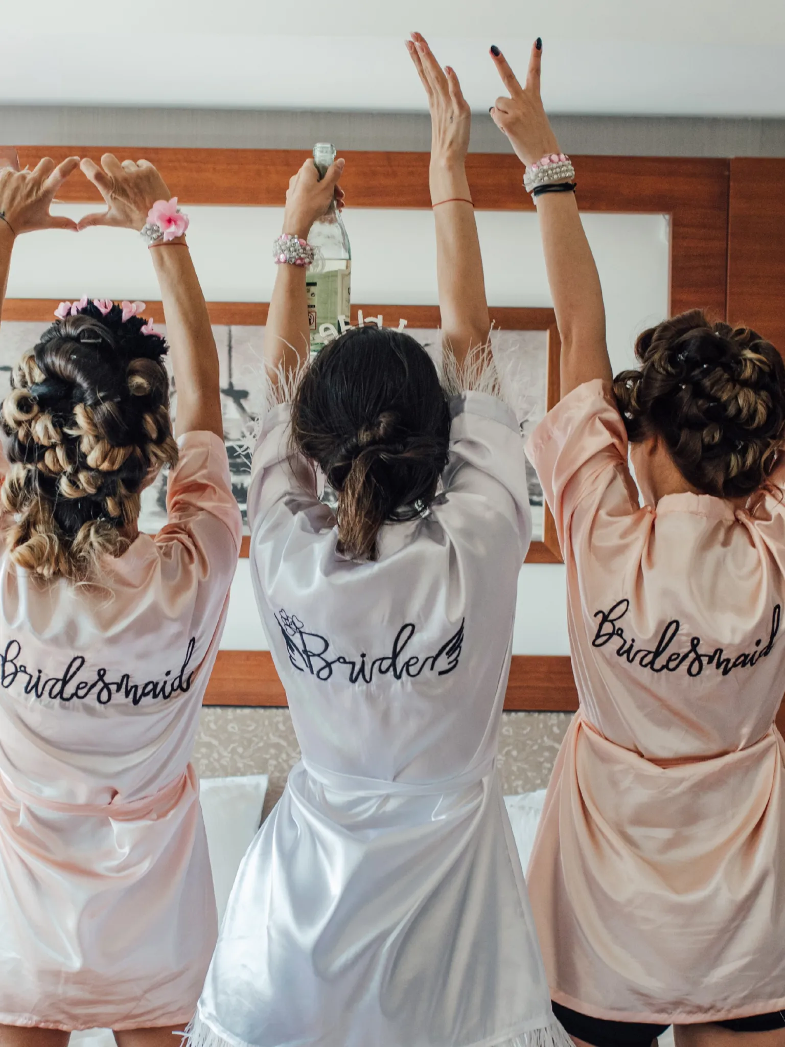 Bridal party with hair in curlers and bridesmaid robes on wearing fun accessories