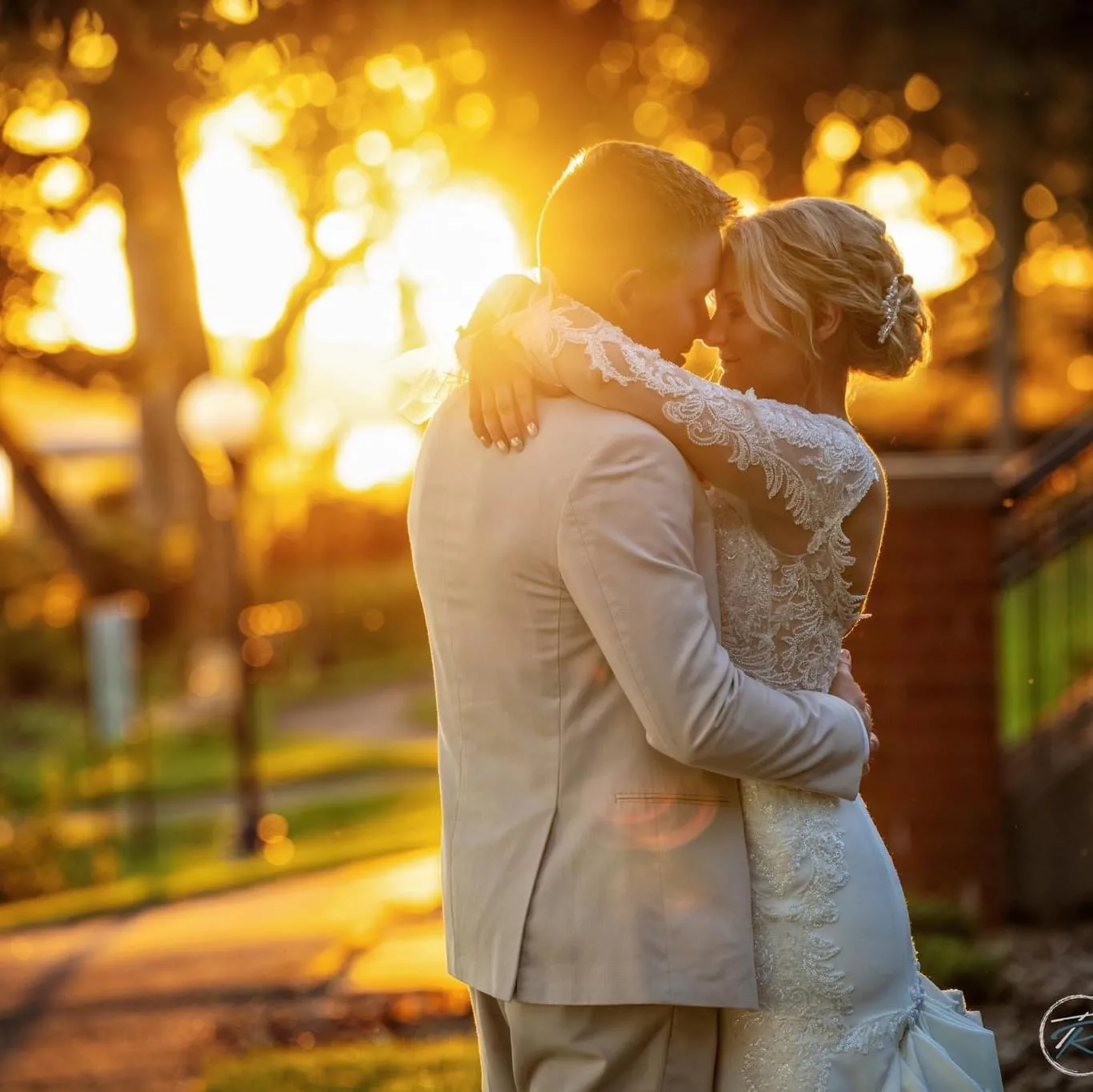 Bride and groom hugging in front of a sunset