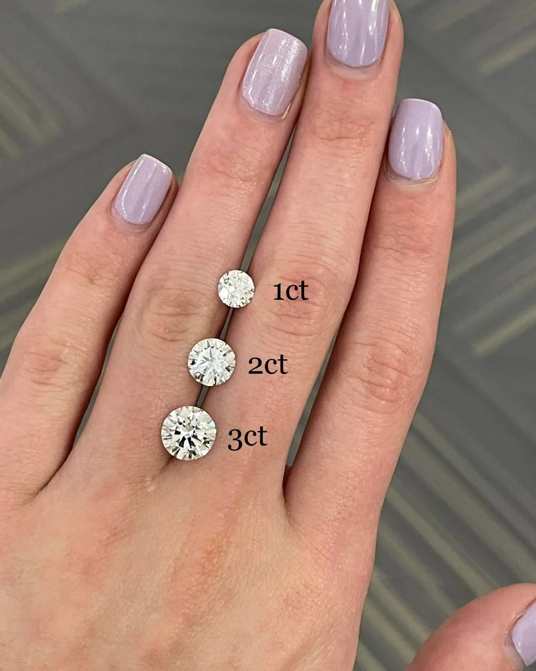 Three rings with large round diamonds in gold and silver settings on a light background.