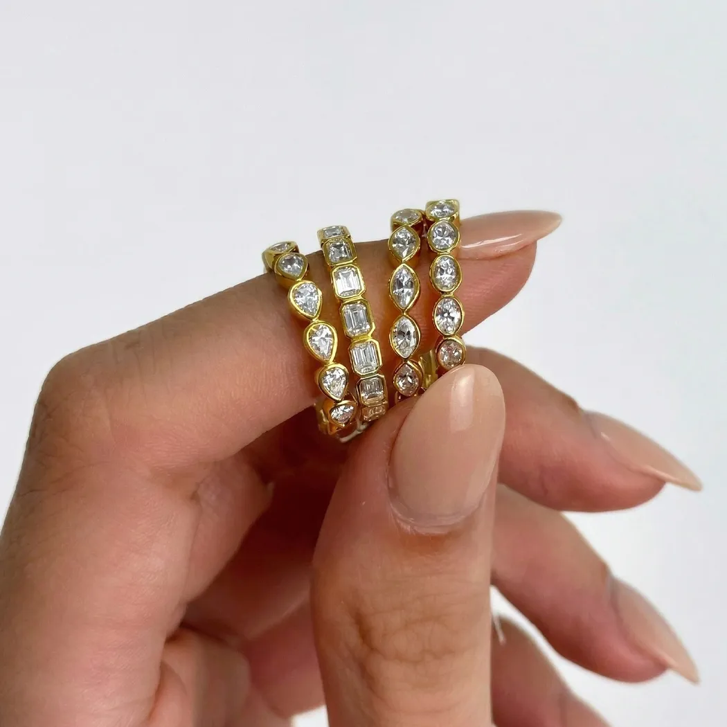 Three gold rings with various diamond cuts held between fingers.