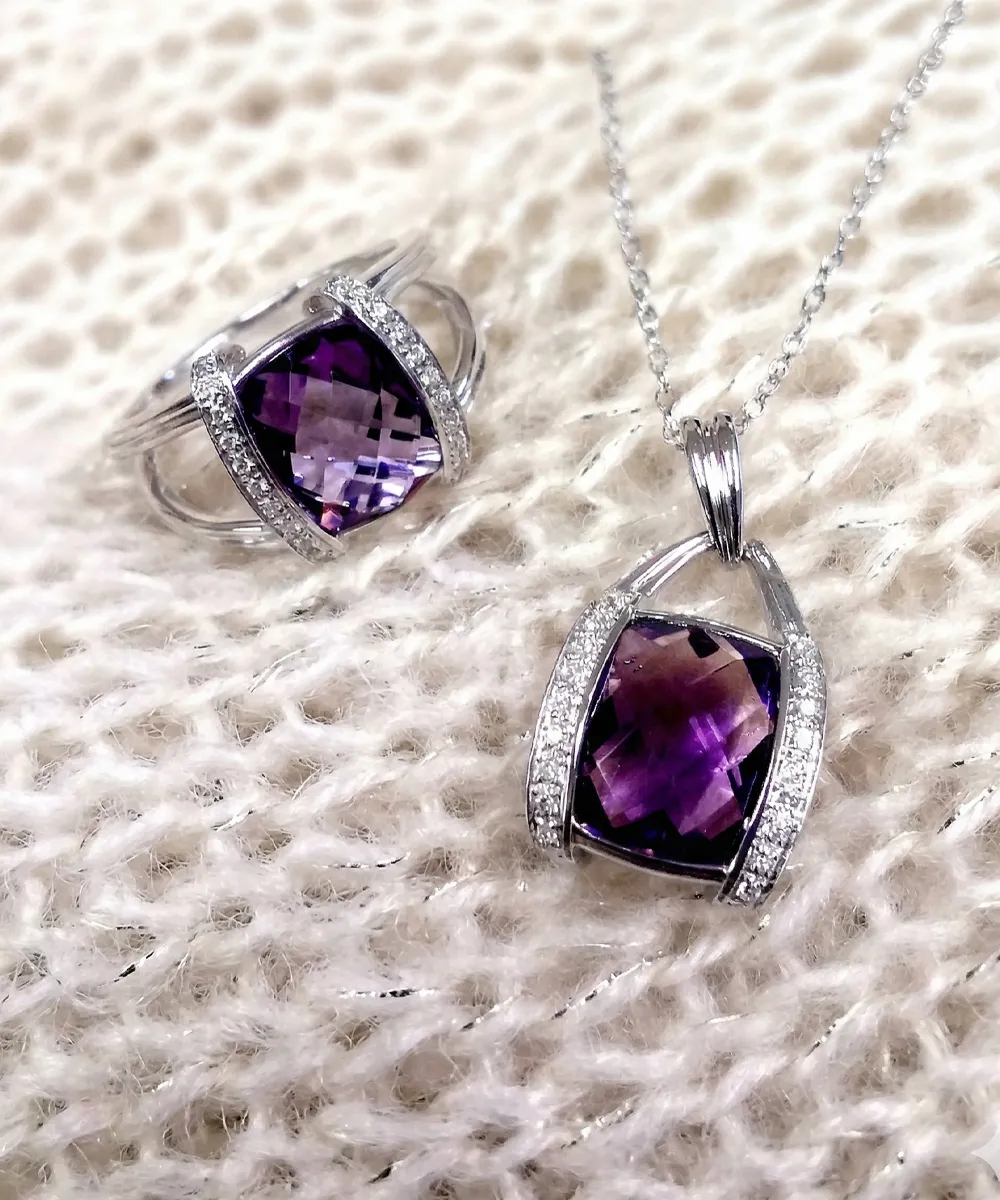 Amethyst ring and pendant set with silver accents on a textured surface.