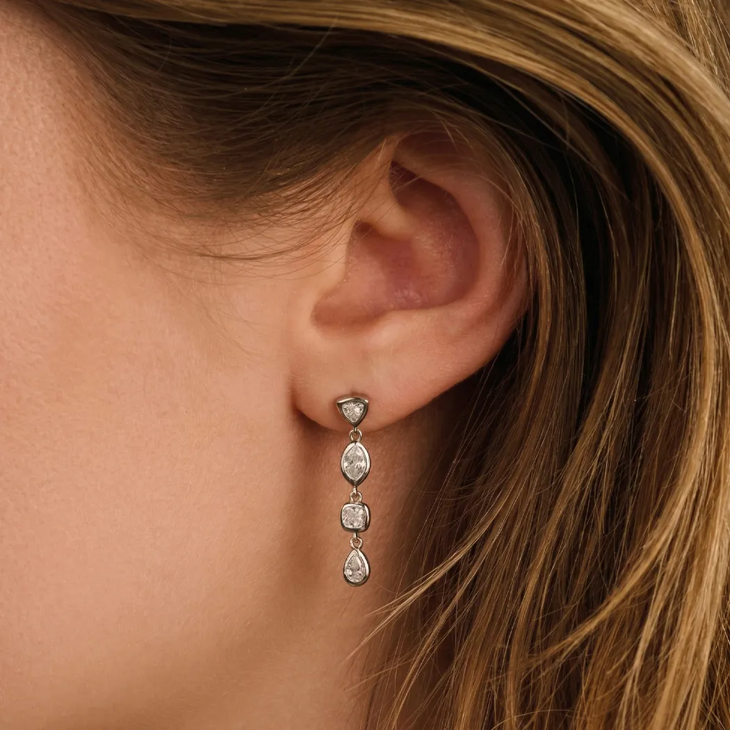 Close-up of a woman's ear wearing a dangling silver earring with multiple stones.