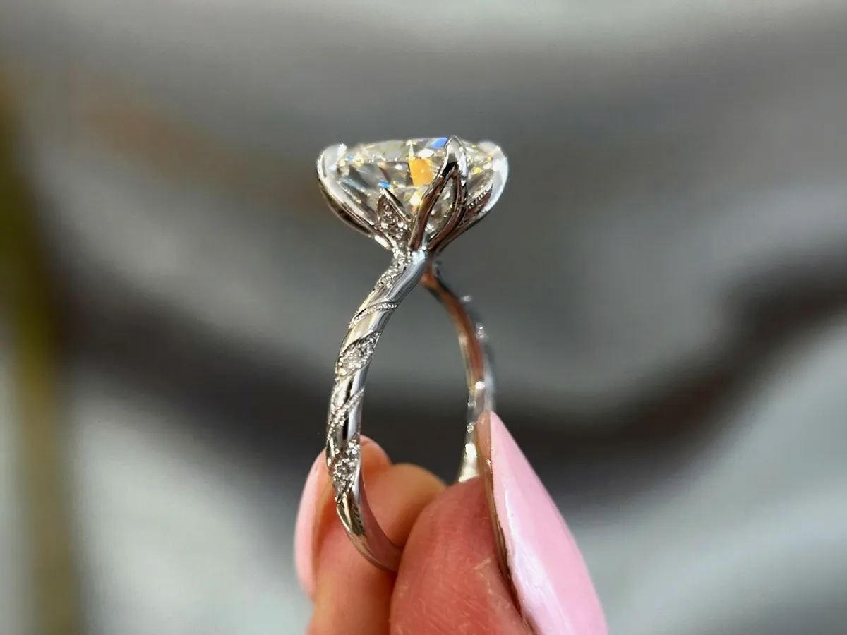 Elegant diamond ring with twisted band held between fingers.