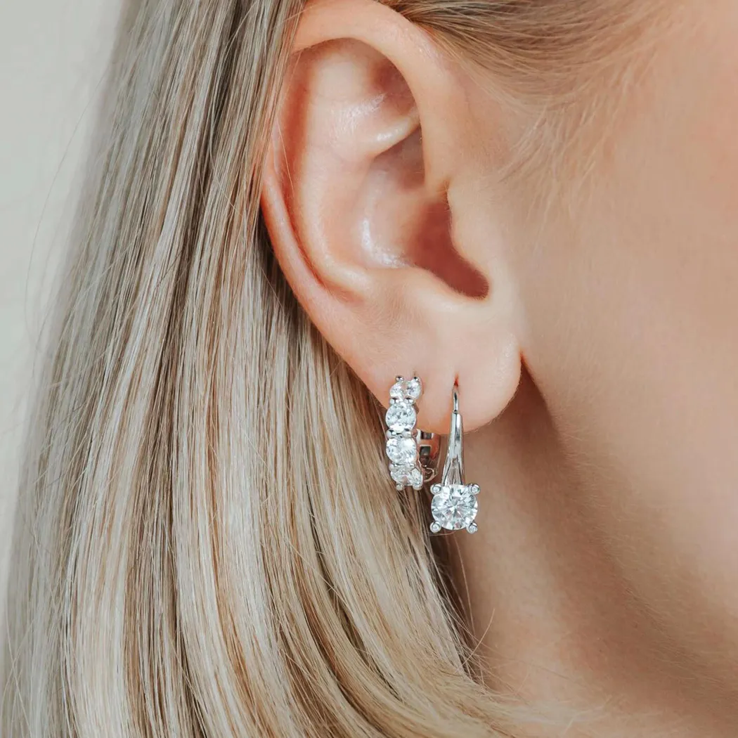 Close-up of a woman's ear wearing sparkling diamond hoop earrings.