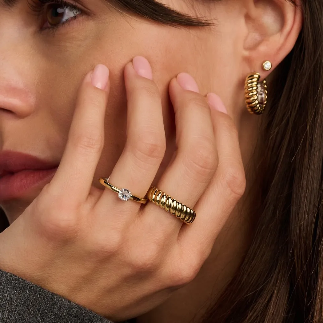 Close-up of a woman's hand with gold rings and earrings, showcasing elegant jewelry.