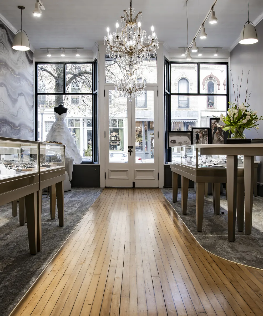 Elegant jewelry store interior with chandeliers, display cases, and a wedding dress in the window.