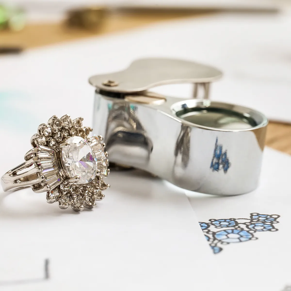 A diamond ring and jeweler's loupe on a design sketch at Diedrich Jewelers.