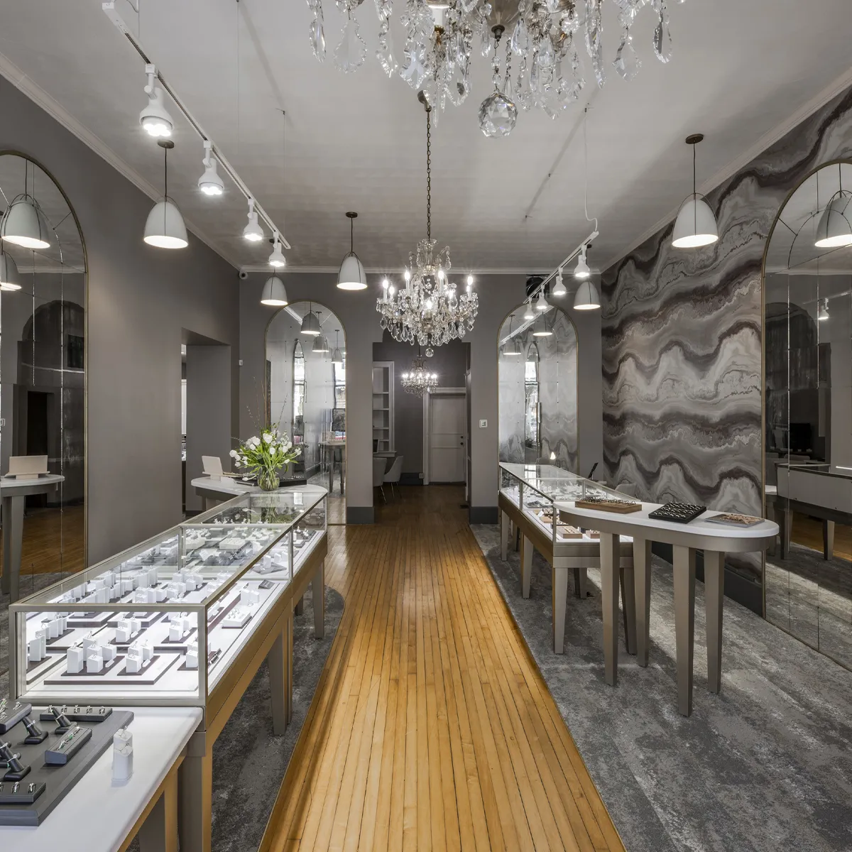 Elegant jewelry store interior with display cases, chandeliers, and decorative mirrors.