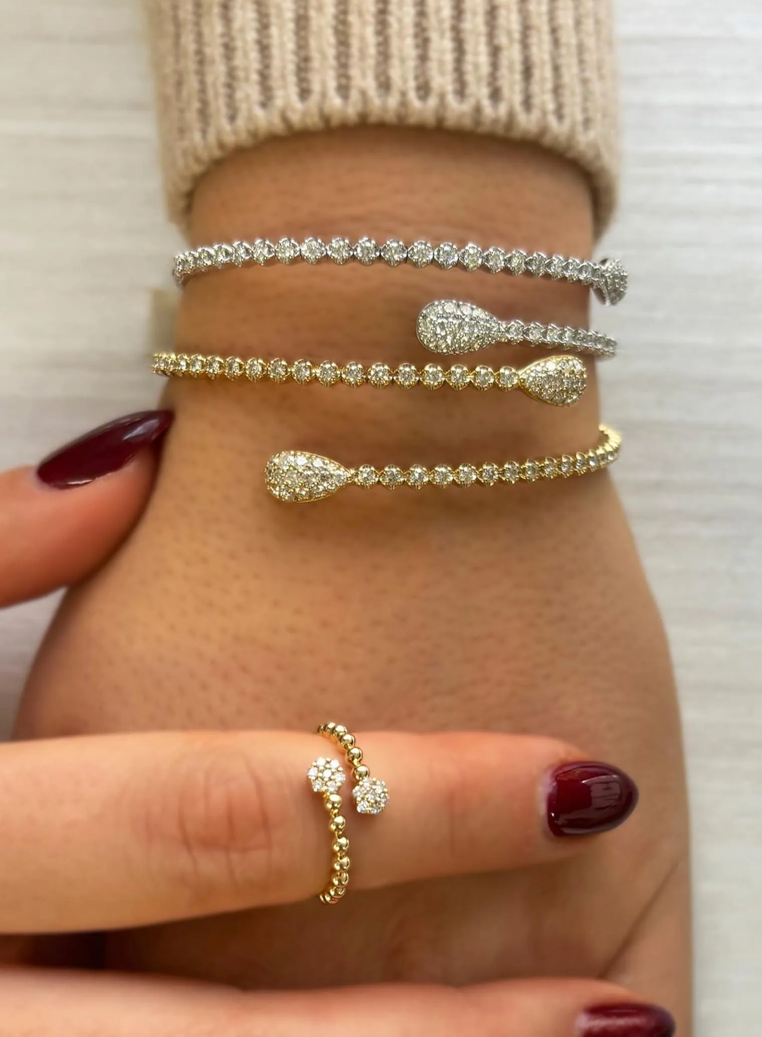 A person wearing an elegant bracelet with a green gemstone centerpiece.
