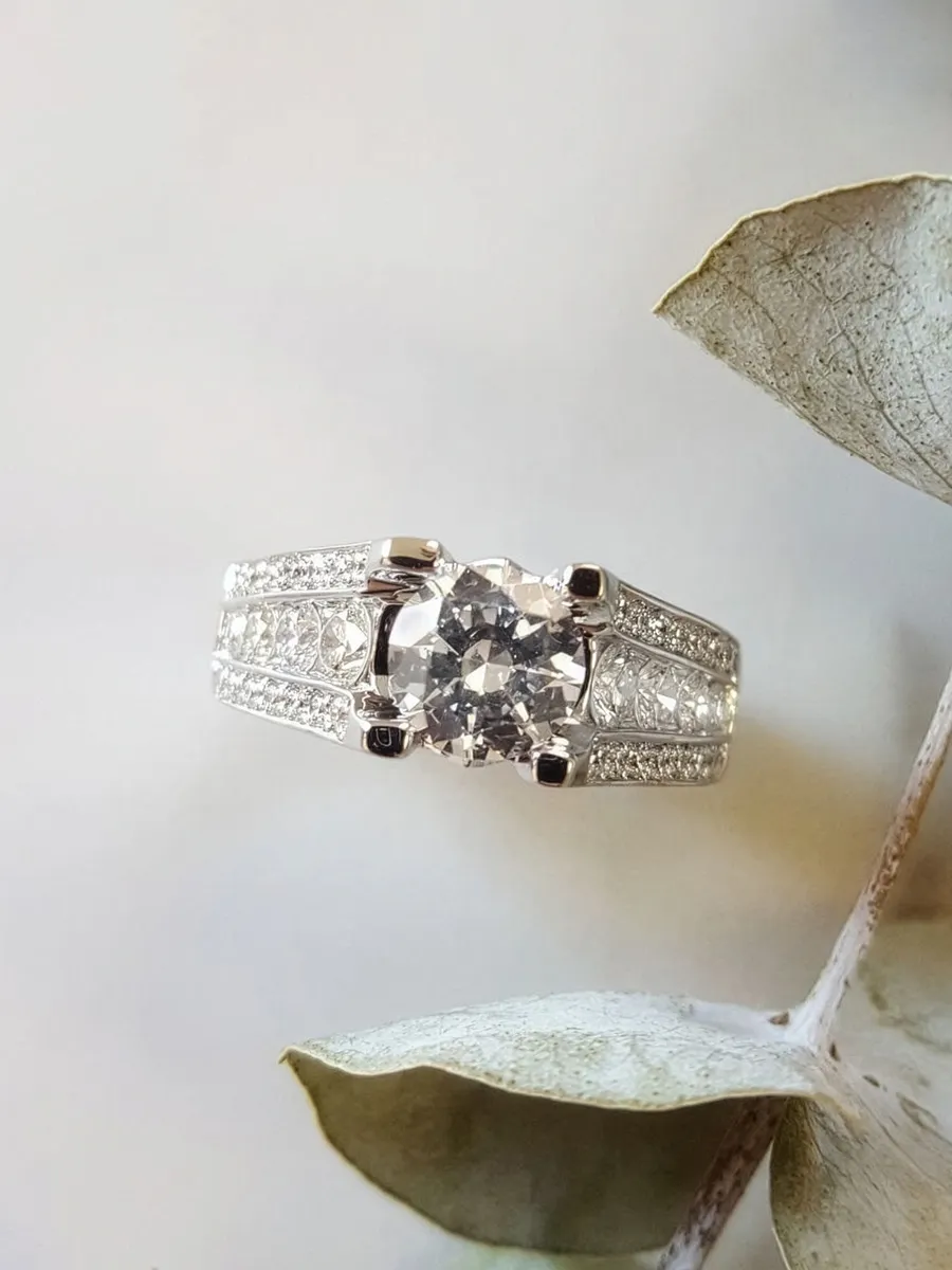 Elegant diamond ring with intricate band design on a light background.
