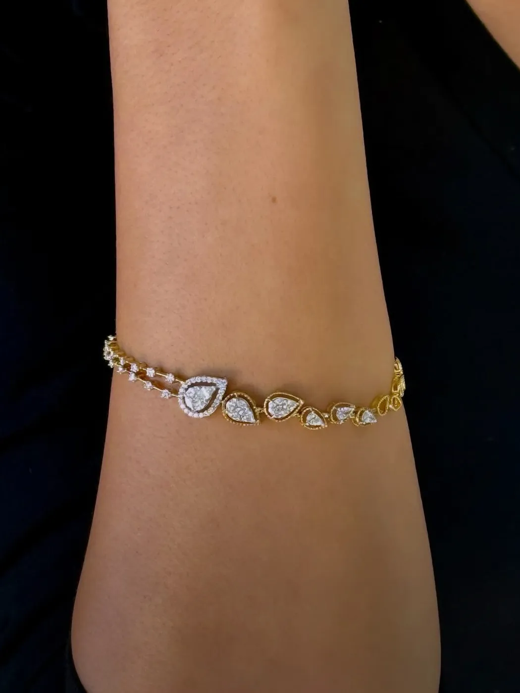 Elegant gold bracelet with teardrop-shaped diamond accents on a wrist.