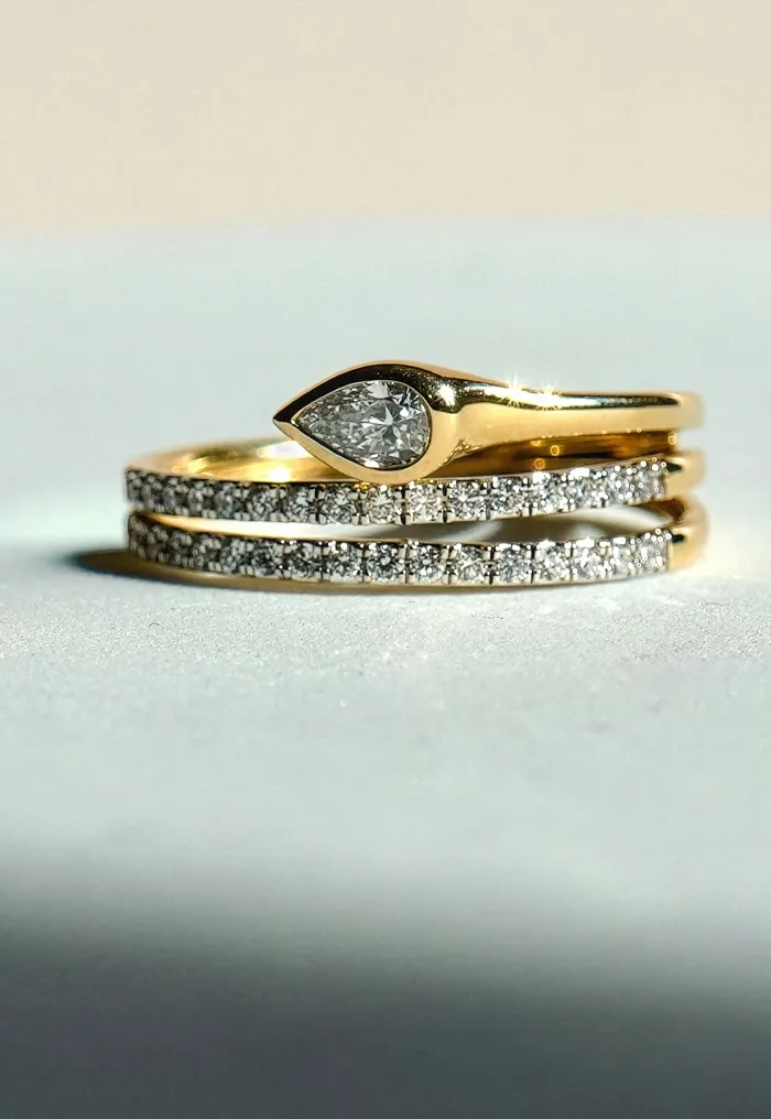 Gold and diamond rings stacked together on a light surface.