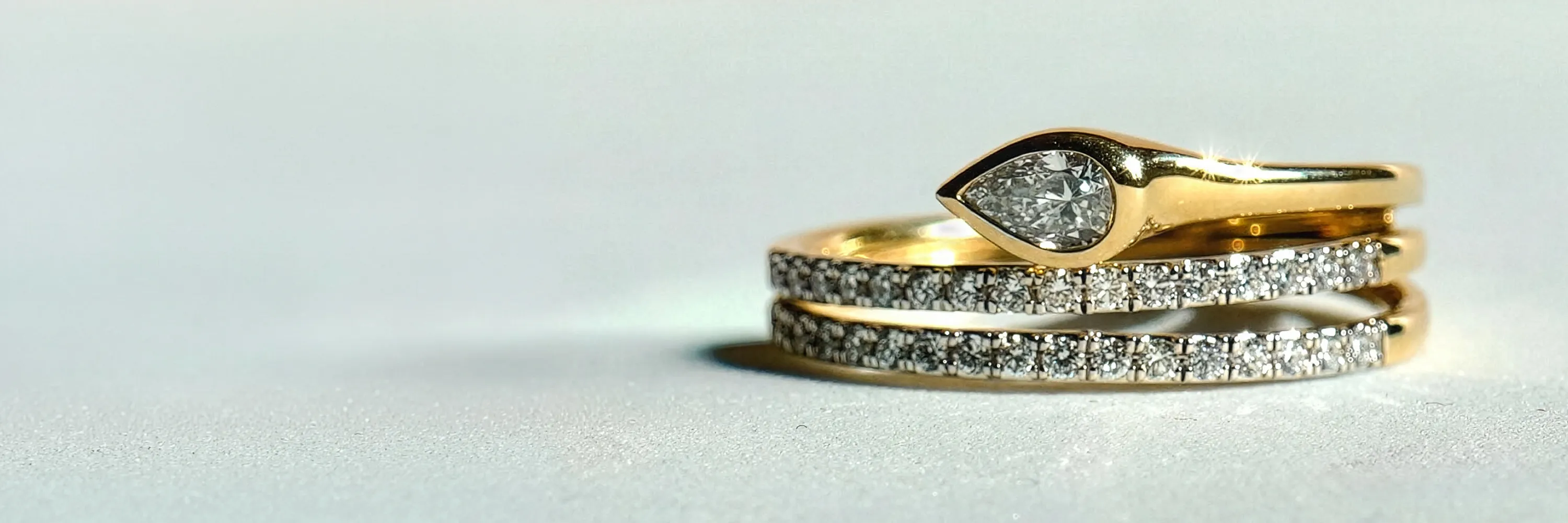 Gold and diamond rings stacked together on a light surface.