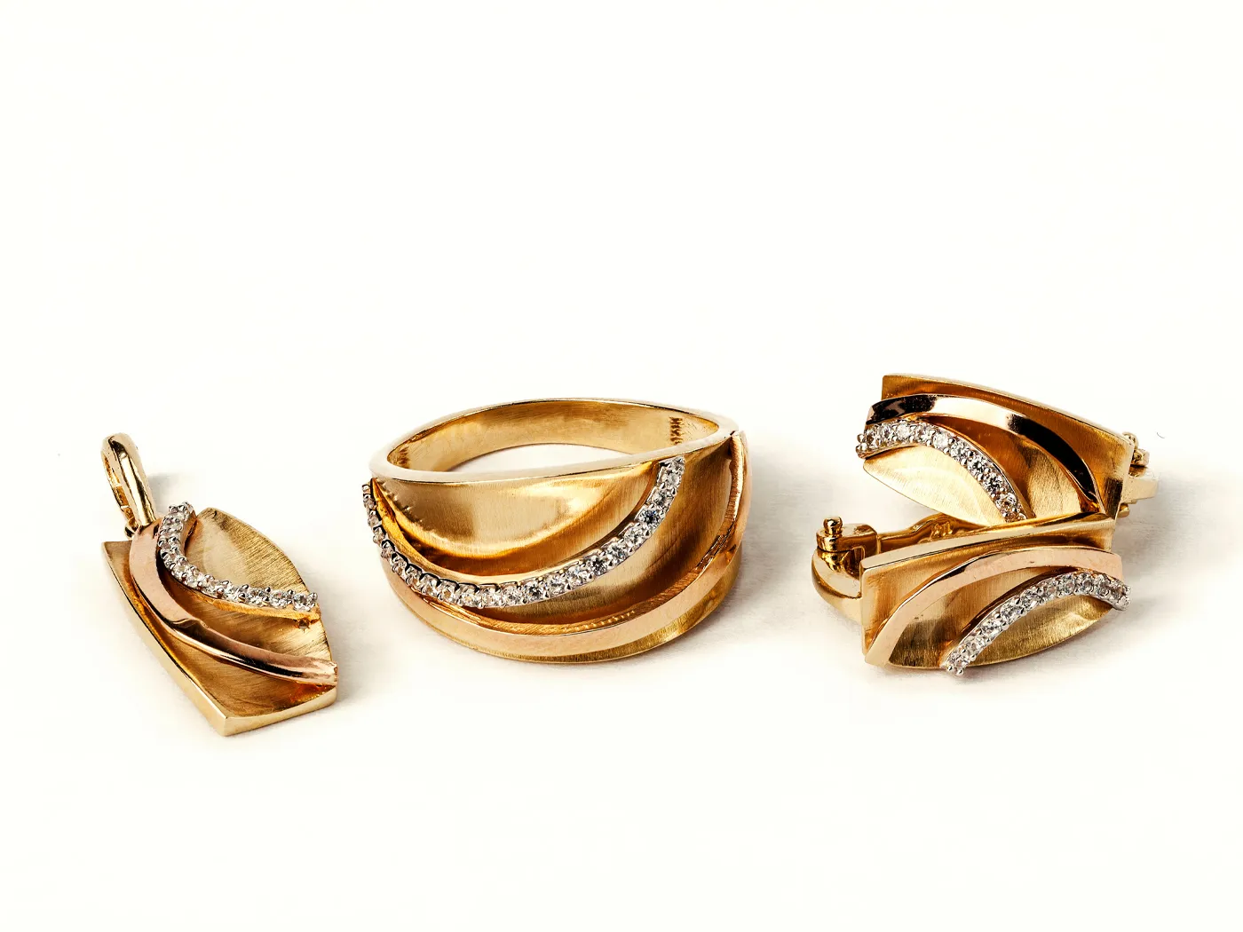 Gold jewelry set featuring a ring, earrings, and pendant with diamond accents.